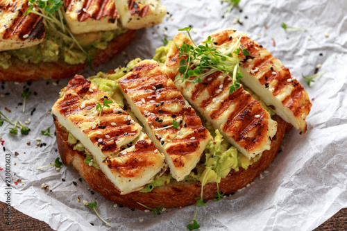 Avocado and grilled haloumi cheese toast with nigella and sesame seeds on crumpled paper. healthy breakfast photo