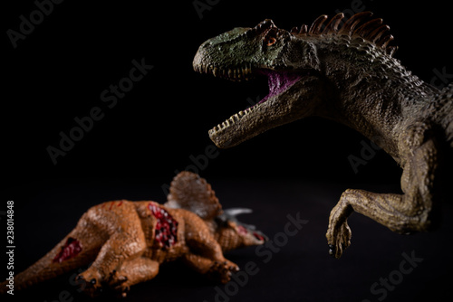 allosaurus  in front of a triceratops body on dark background © Freer