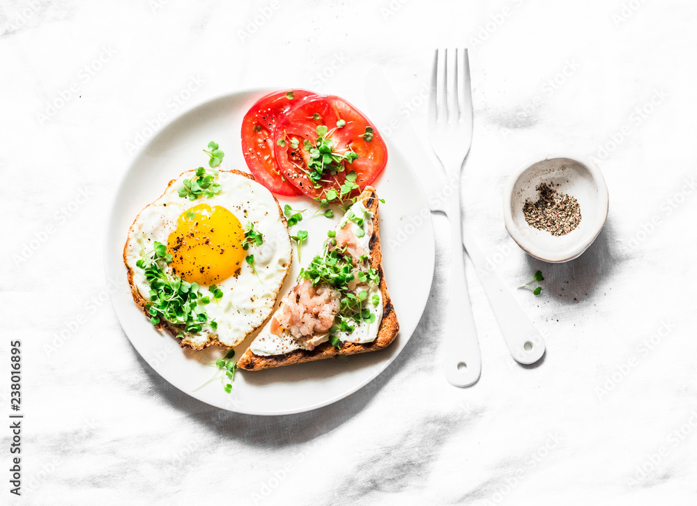 Breakfast served - fried egg, smoked mackerel cream cheese toast, tomatoes on a light background, top view