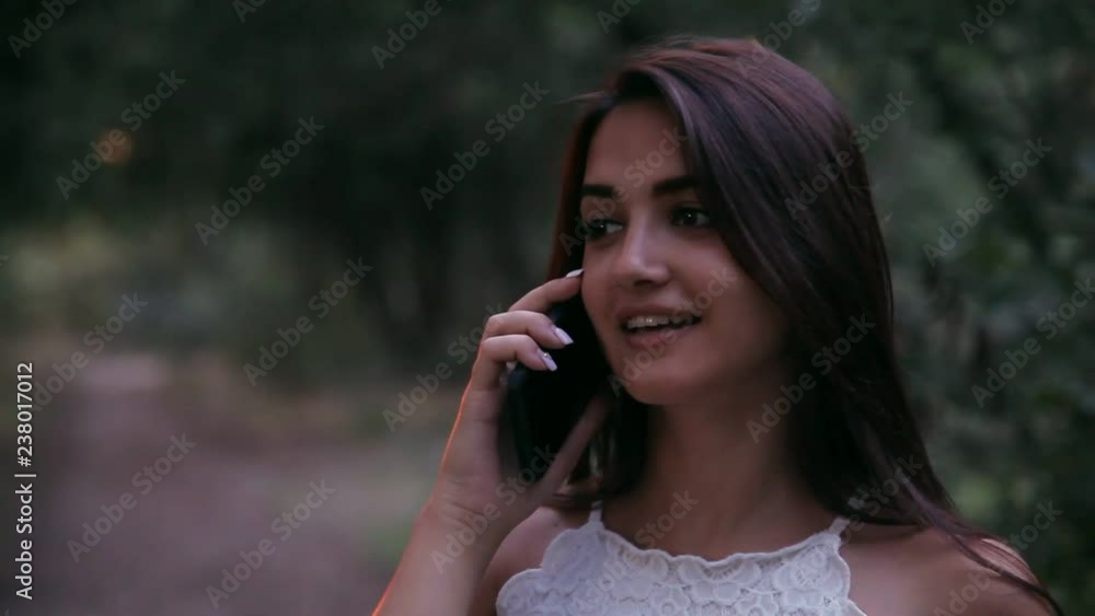 young laughing woman talking on the phone at sunset in the park young laughing woman talking on the phone at sunset in the park