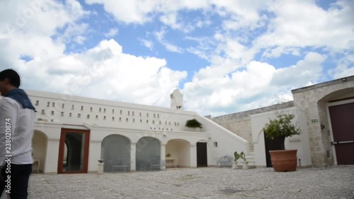 Giovane uomo cammina all'interno di un cortile di un'antica masseria pugliese photo