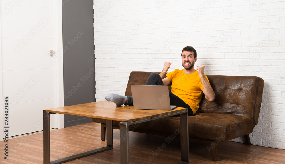 Man with his laptop in a room frustrated by a bad situation Man with his laptop in a room frustrated by a bad situation