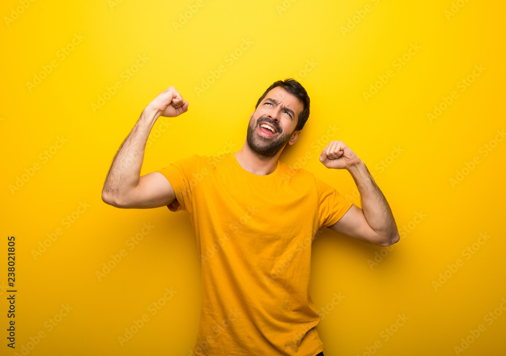Man on isolated vibrant yellow color celebrating a victory in winner position Man on isolated vibrant yellow color celebrating a victory in winner position