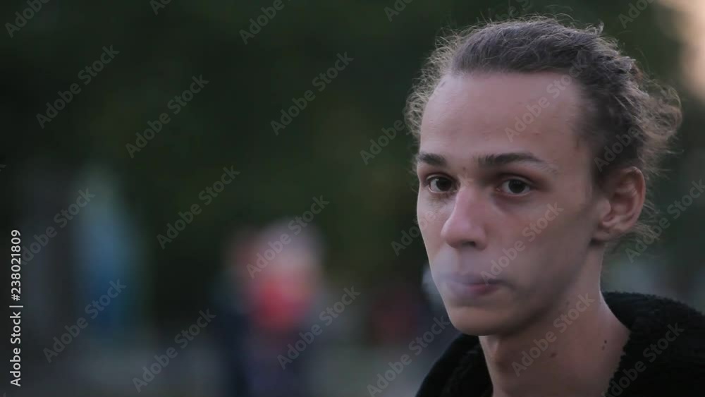 young guy smokes cigarette outdoors in the evening young guy smokes cigarette outdoors in the evening