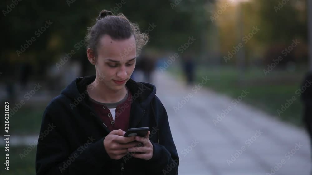 young curly man using mobile phone outdoors in the evening young curly man using mobile phone outdoors in the evening