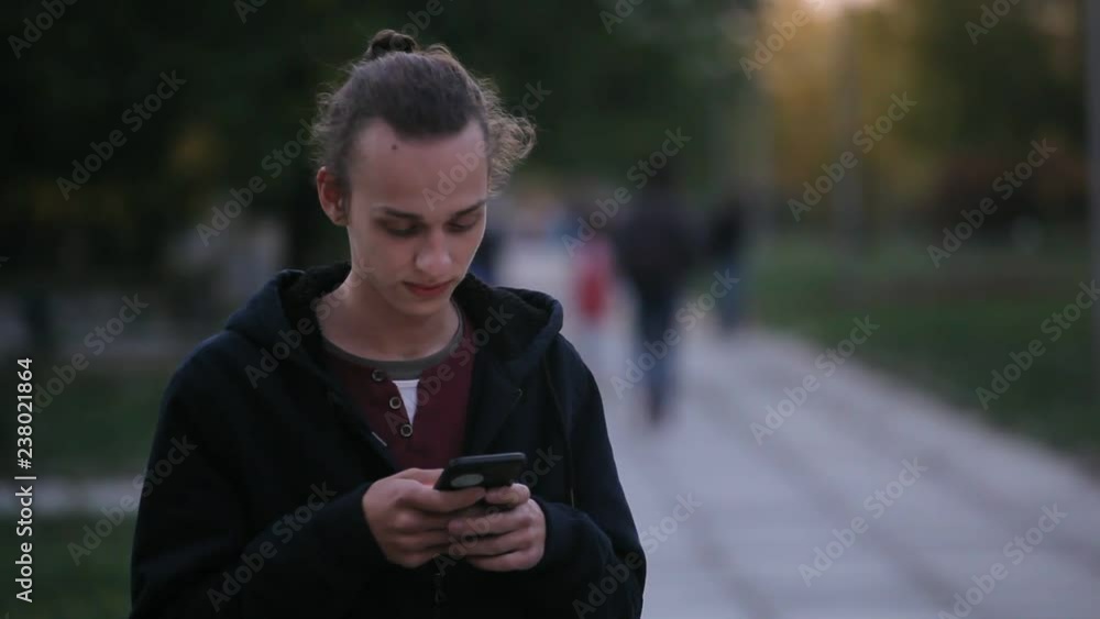 young curly man using mobile phone outdoors in the evening young curly man using mobile phone outdoors in the evening
