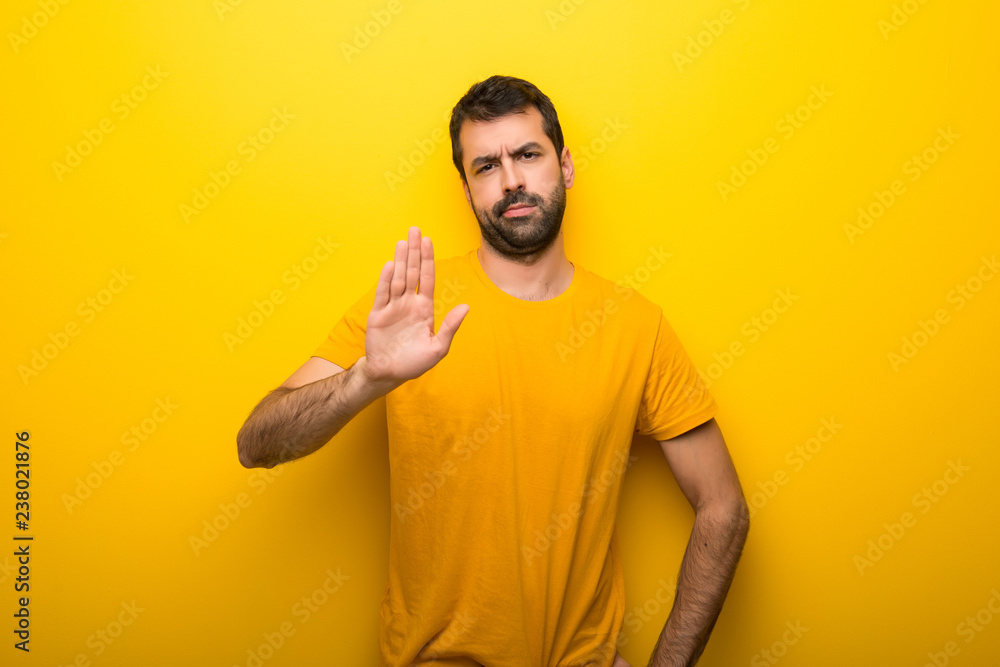 Man on isolated vibrant yellow color making stop gesture denying a situation that thinks wrong Man on isolated vibrant yellow color making stop gesture denying a situation that thinks wrong