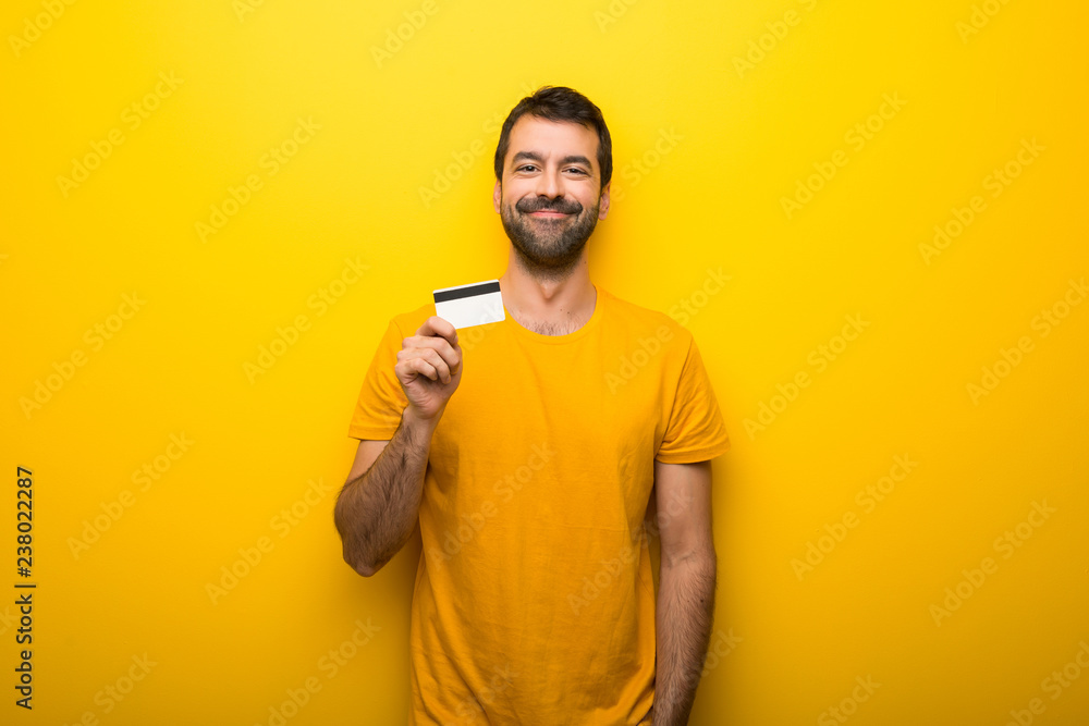 Man on isolated vibrant yellow color holding a credit card Man on isolated vibrant yellow color holding a credit card