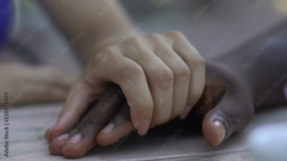 Caucasian woman holding hand of her african-american boyfriend, tenderness Caucasian woman holding hand of her african-american boyfriend, tenderness