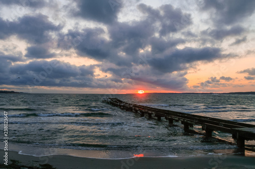 seascape with romantic pier  clouds and waves at sunrise