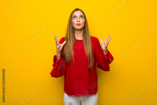 Young girl with red dress over yellow wall frustrated by a bad situation