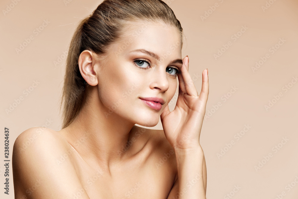 Naklejka premium Attractive young girl touching her face on beige background. Youth and skin care concept