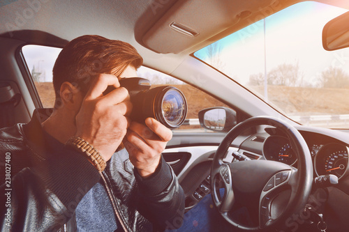 A man is taking pictures from a car window. Photographer traveler. The work of a private detective.