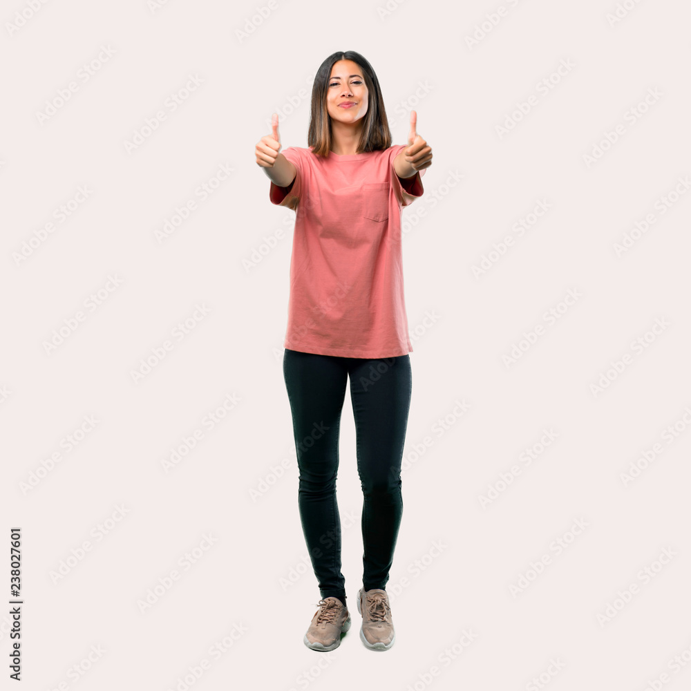 Full body of Young girl with pink shirt giving a thumbs up gesture with both hands and smiling. Cheerful expression Full body of Young girl with pink shirt giving a thumbs up gesture with both hands and smiling. Cheerful expression
