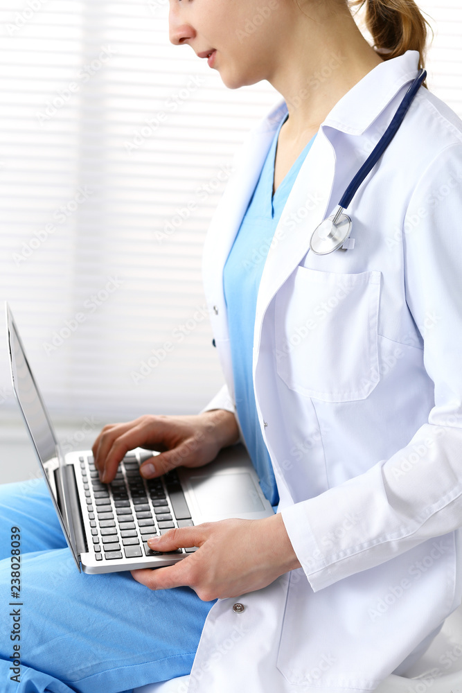 Woman doctor typing on laptop computer while working in hospital office. Data in medicine and health care Woman doctor typing on laptop computer while working in hospital office. Data in medicine and health care
