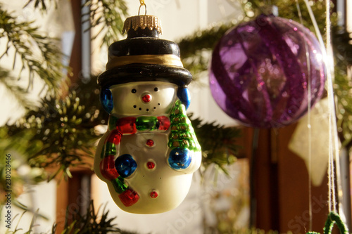Schneemann Dekoration an Weihnachtsbaum mit Kugel in lila und Licht Reflexion
