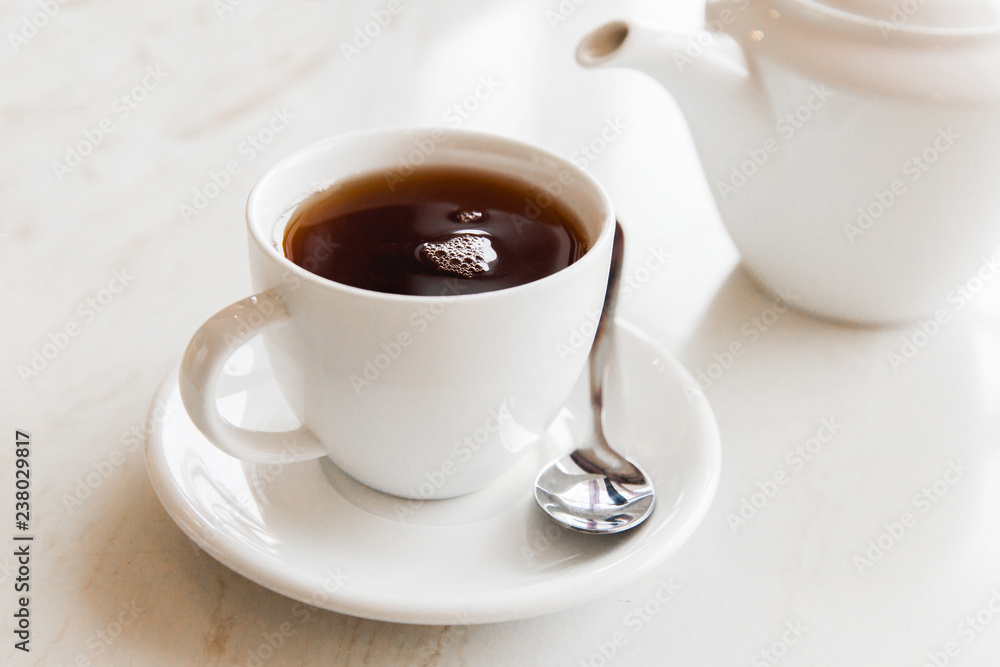 White cu of black tea on white table in the cafe. Breakfast with cup of tea White cu of black tea on white table in the cafe. Breakfast with cup of tea