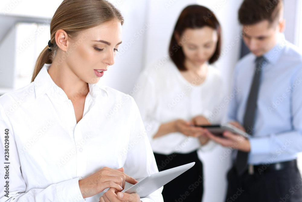 Beautiful blonde businesswoman standing straight in a brightly lit office at the background of colleagues or partners. Business concept Beautiful blonde businesswoman standing straight in a brightly lit office at the background of colleagues or partners. Business concept