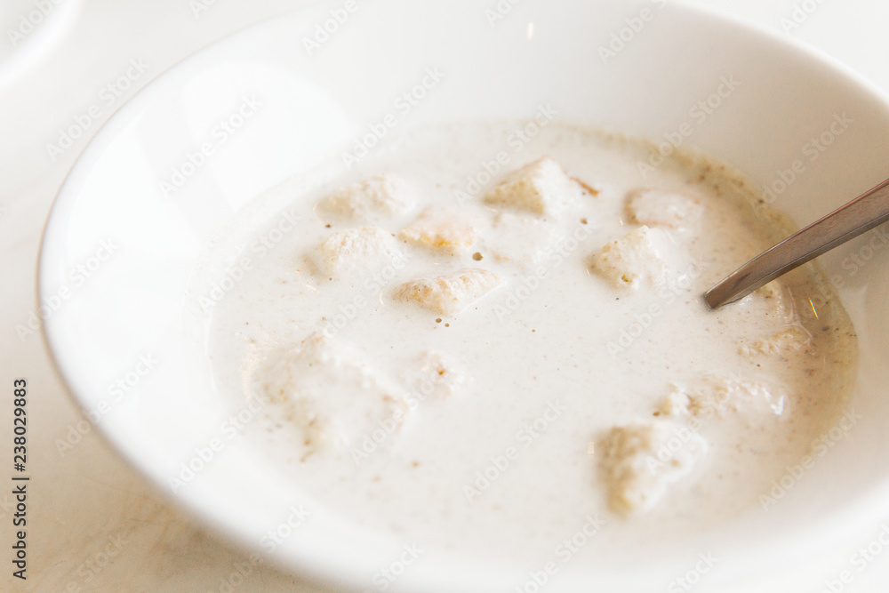 Cream-soup with champignons in white bowl on white table in the restaurant Cream-soup with champignons in white bowl on white table in the restaurant