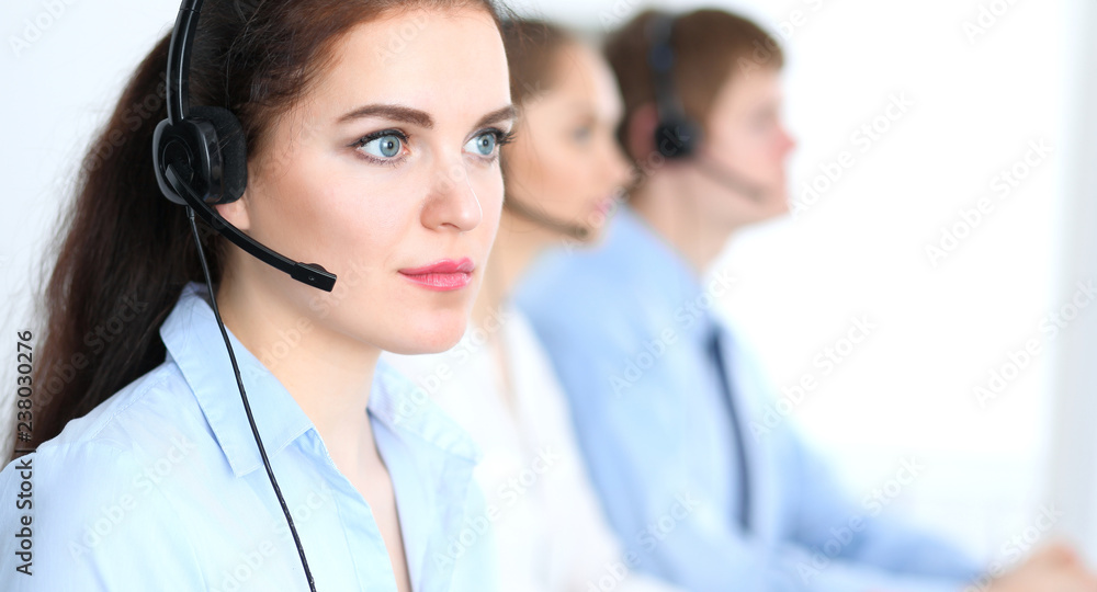 Call center operators at work. Focus at business woman in headset Call center operators at work. Focus at business woman in headset