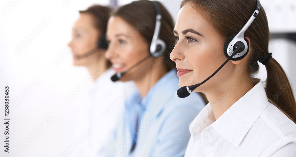 Call center. Group of operators at work. Focus at beautiful business woman in headset Call center. Group of operators at work. Focus at beautiful business woman in headset