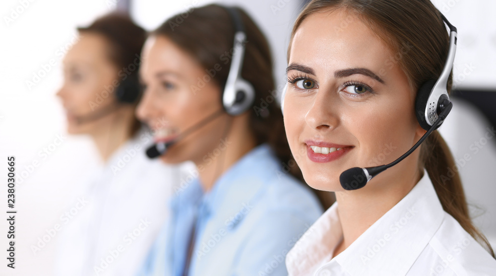 Call center. Group of operators at work. Focus at beautiful business woman in headset Call center. Group of operators at work. Focus at beautiful business woman in headset