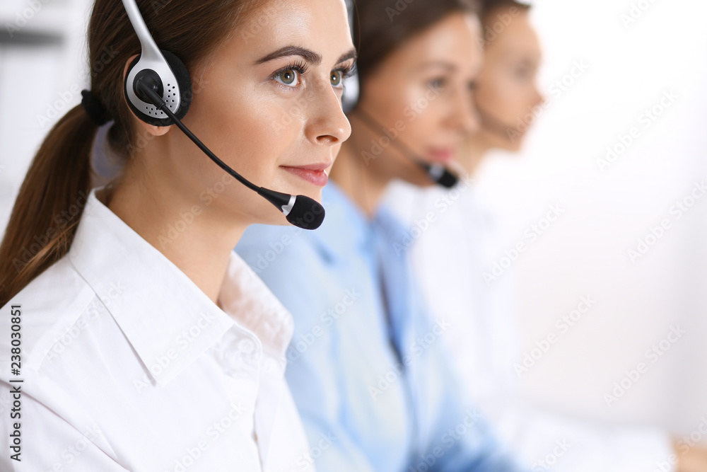 Call center. Group of operators at work. Focus at beautiful business woman in headset Call center. Group of operators at work. Focus at beautiful business woman in headset