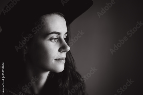 Calm portrait of beautiful young woman wearing black hat . Black and white photo