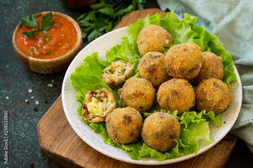 Arancini - traditional Italian Rice Balls with Mozzarella and Sun-dried tomatoes, served with tomato sauce.