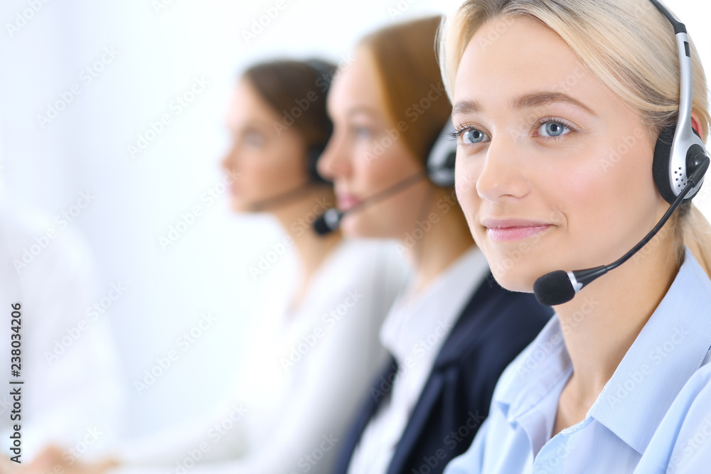 Call center. Group of operators at work. Focus at blonde business woman in headset Call center. Group of operators at work. Focus at blonde business woman in headset