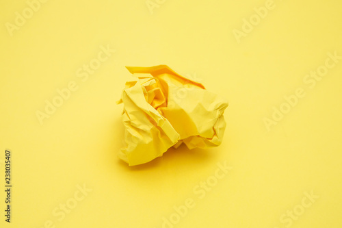 Yellow piece of crumpled paper on yellow background