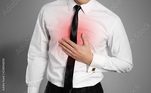 Businessman in a white shirt and tie holding his chest. Chest pain. Heartburn. Isolated background