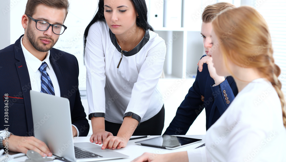 Business people team at meeting in office. Focus at business woman pointing into laptop. Teamwork or coaching concepts Business people team at meeting in office. Focus at business woman pointing into laptop. Teamwork or coaching concepts