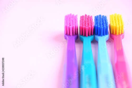 Colorful toothbrushes with selective focus on pink background. Toothbrush for personal routine morning  hygiene on neutral blurred backdrop. Dental plastic tool with empty space for image or text