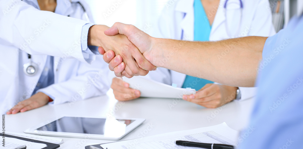 Two doctors shaking hands to each other at meeting. Teamwork and agreement in medicine Two doctors shaking hands to each other at meeting. Teamwork and agreement in medicine