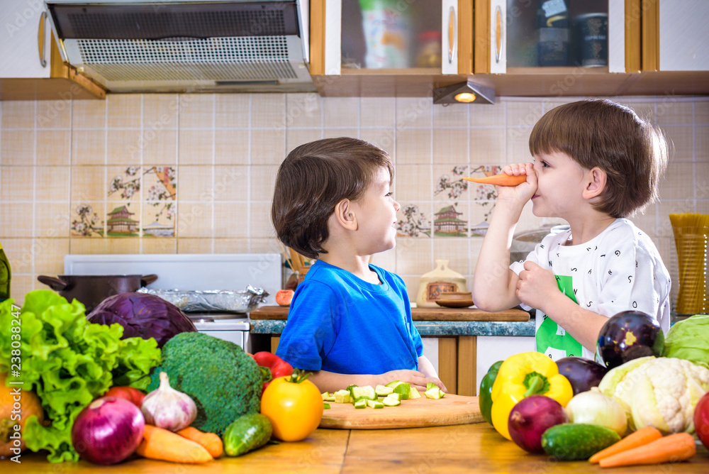 Fototapeta premium Healthy eating. Happy children prepares and eats vegetable salad in kitchen