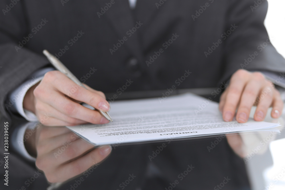 Fototapeta premium Close-up of female hands with pen over document, business concept. Lawyer or business woman at work in office