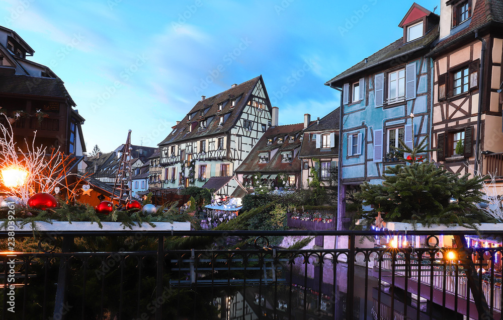 Traditional Alsatian half-timbered houses in old town of Colmar and branches of Christmas tree in the foreground.