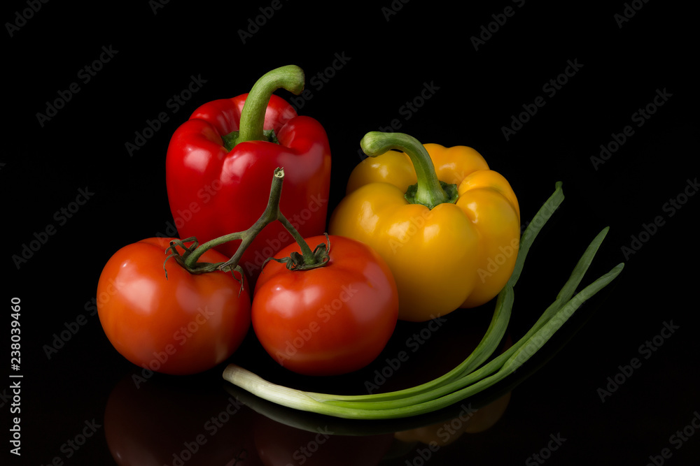 Fresh, appetizing vegetables lie on a dark reflective surface on a black background. Fresh, appetizing vegetables lie on a dark reflective surface on a black background.
