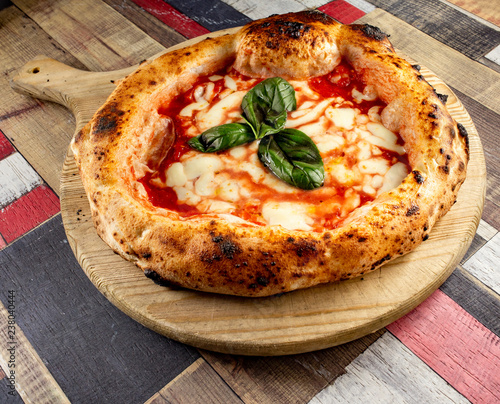Italian Pizza in chopping board on a wooden table