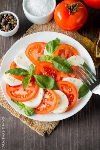 Close-up photo of caprese salad with ripe tomatoes, basil, buffalo mozzarella cheese. Italian and Mediterranean food concept. Fresh and healthy organic meal. Starter and antipasti. 