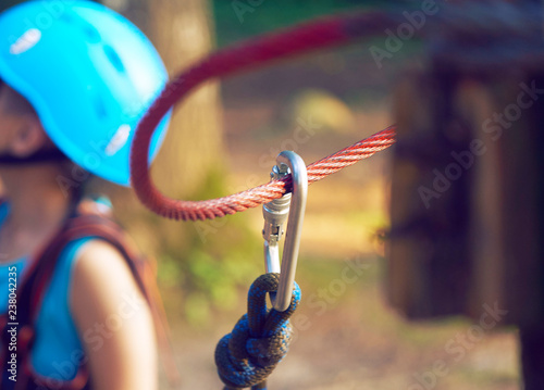 Cute little boy in blue shirt and helmet having fun at the adventure park, holding ropes and preparing to climb wooden stairs. Hobby, active lifestyle concept. © cameravit