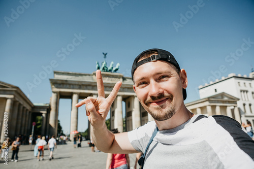 Photography Tourist guy makes selfie on the background of the Brandenburg Gate in Berlin in