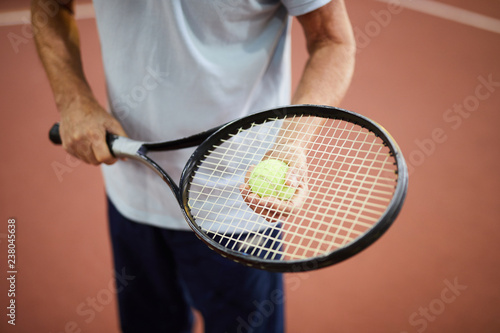 Contemporary tennis player holding racket and ball while standing on stadium © pressmaster