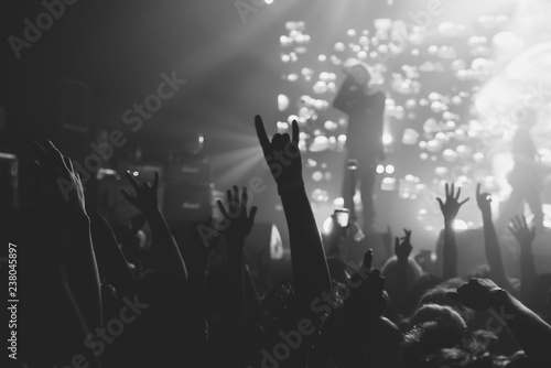 Hands of a crowd raised up at the music show to the singer on stage. Black and white. Black and white