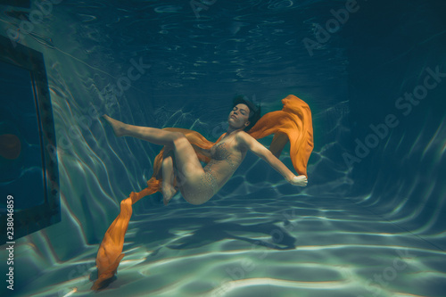 cute sporty girl swims underwater as a free diver in lingerie and mesh catsuit with rhinestones alone