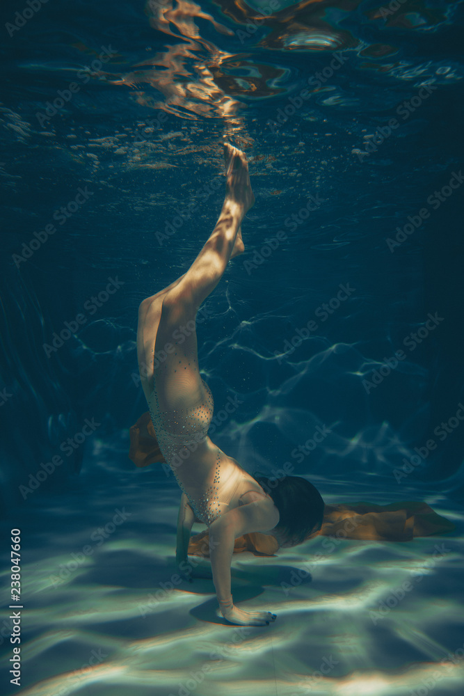 cute sporty girl swims underwater as a free diver in lingerie and mesh  catsuit with rhinestones alone Photos | Adobe Stock