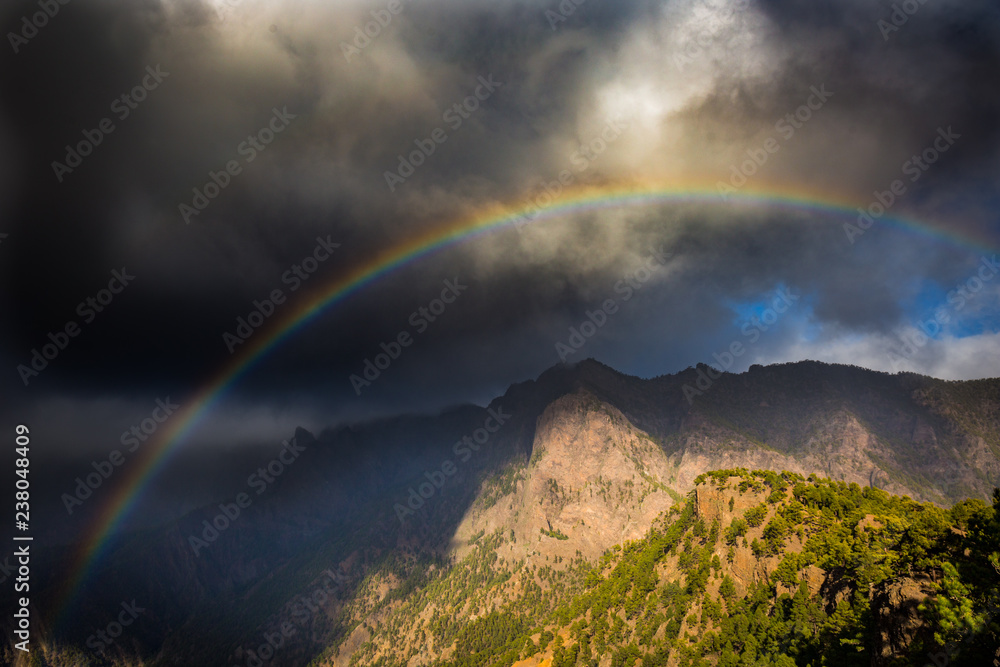 rainbow in front of mountains during stormy weather