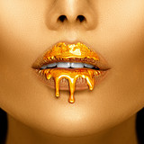 Gold paint drips from the sexy lips, golden liquid drops on beautiful model girl's mouth, creative abstract makeup. Beauty woman face