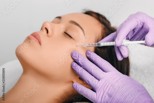 Woman receiving Botulinum Toxin Injection injection into eyes area .